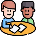 Two people are sitting together at a table discussing a contract.